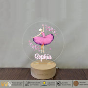 a glass ballerina with a pink tutu on a wooden stand