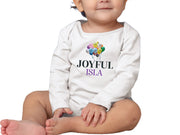 a baby sitting on the ground wearing a white shirt with colorful balloons on it