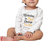 a baby sitting on the ground wearing a birthday shirt