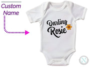a baby bodysuit with the words, custom name and a picture of a flower