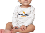 a baby sitting on the floor wearing a t - shirt with a star on it