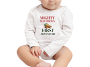 a baby sitting on the ground wearing a white onesie