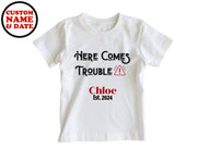 a white bodysuit with the words here comes trouble on it