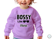 a little girl wearing a purple sweatshirt that says bossy like olvia