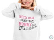 a girl wearing a sweatshirt that says messy hair don't care mommy loves it