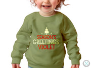 a little girl wearing a green sweatshirt with a christmas tree on it